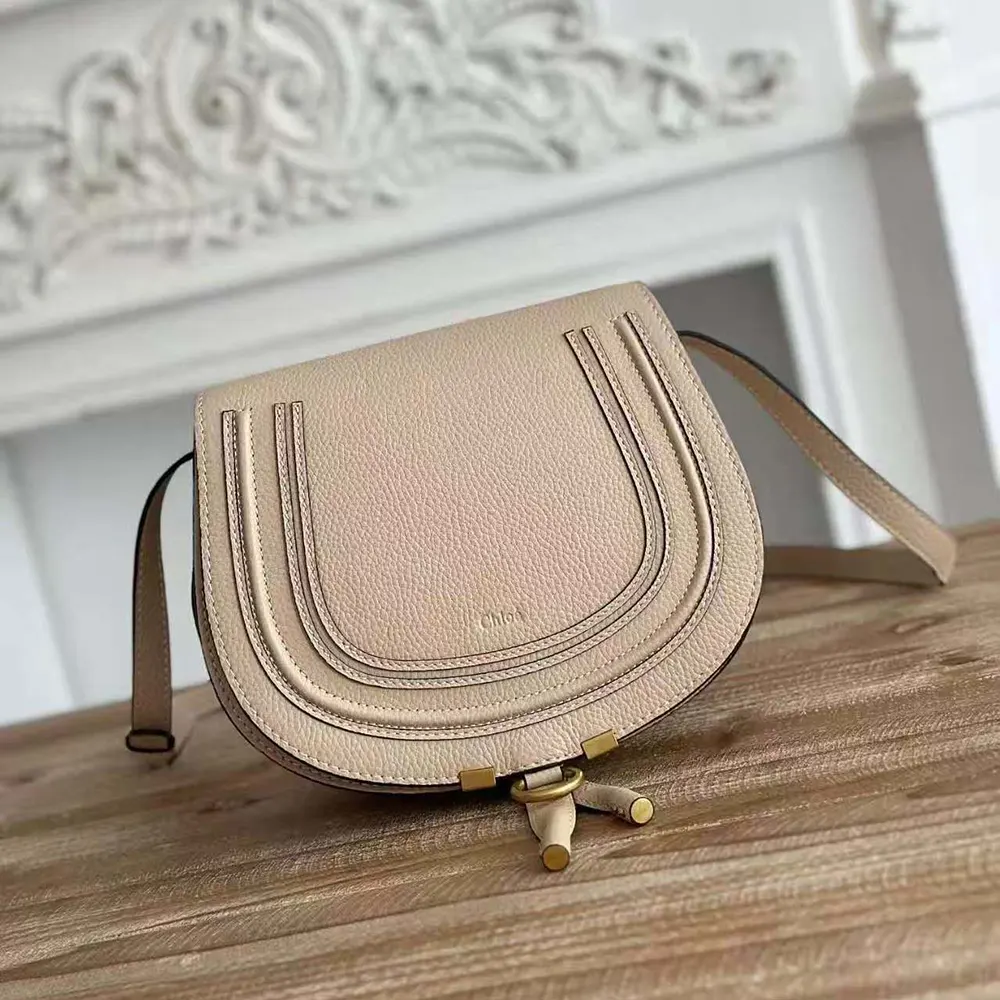 Close-up of gold-tone closure on Chloe Women Marcie Small Saddle Bag-Sandy