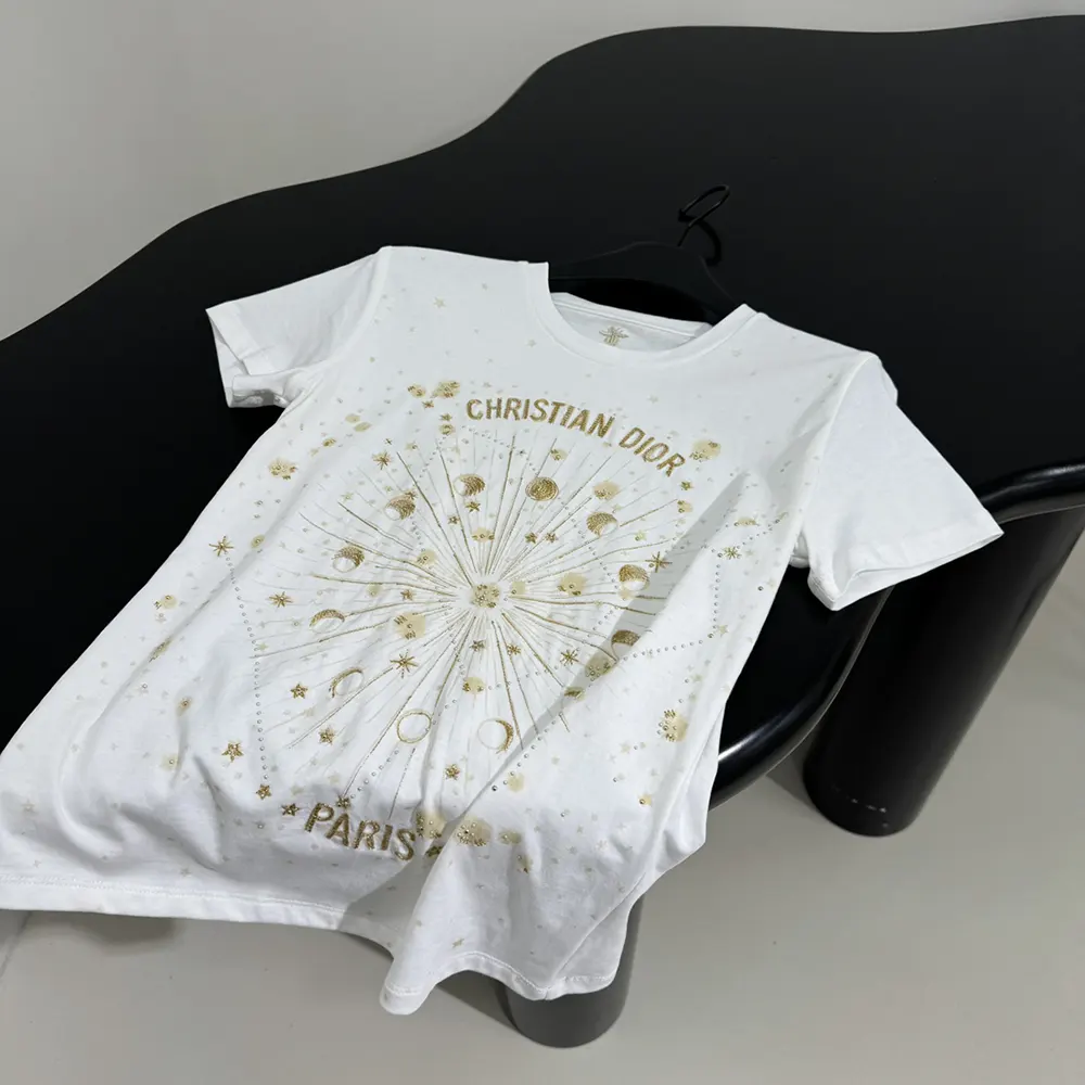 Close-up of gold-tone Dior Astral embroidery on white cotton jersey