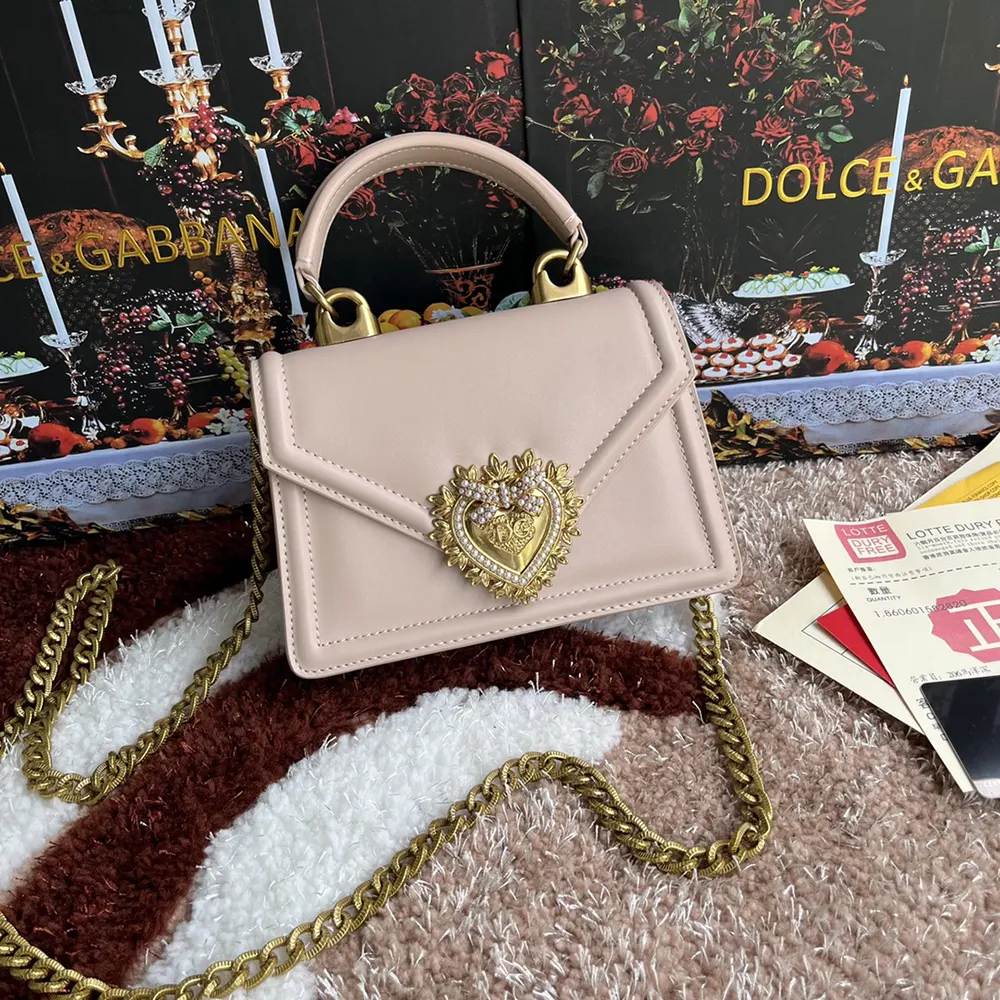 Close-up of gold devotion heart clasp on pink calfskin bag