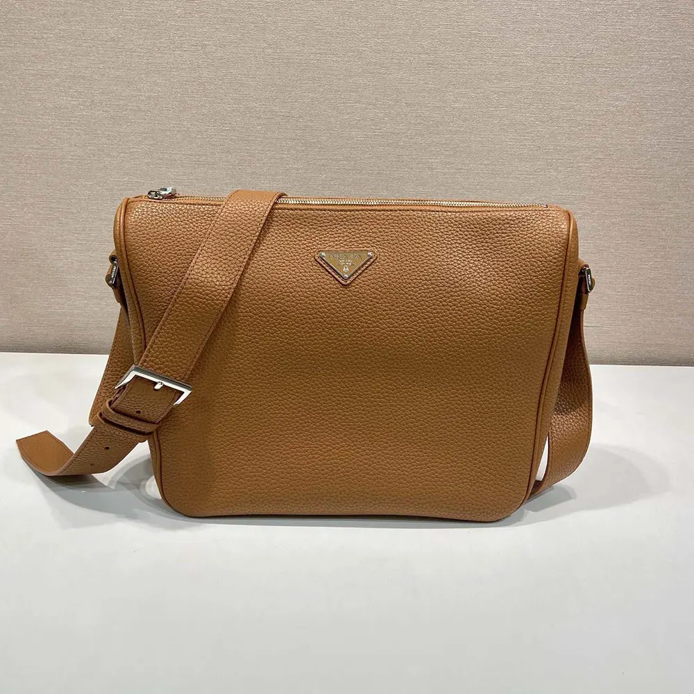 Close-up of gold-tone Prada logo on brown leather shoulder bag