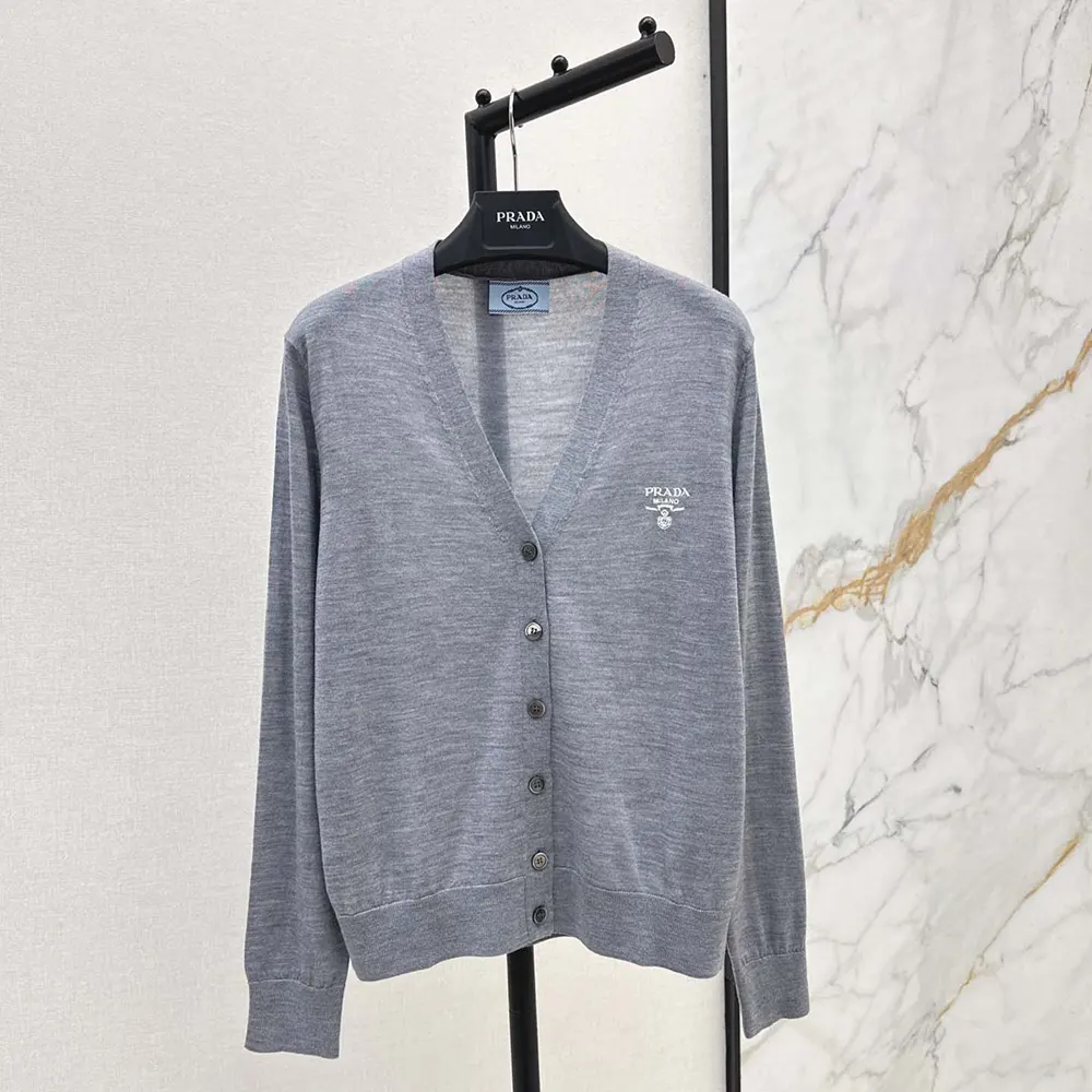 Close-up of Prada logo embossed buttons on the gray cashmere cardigan