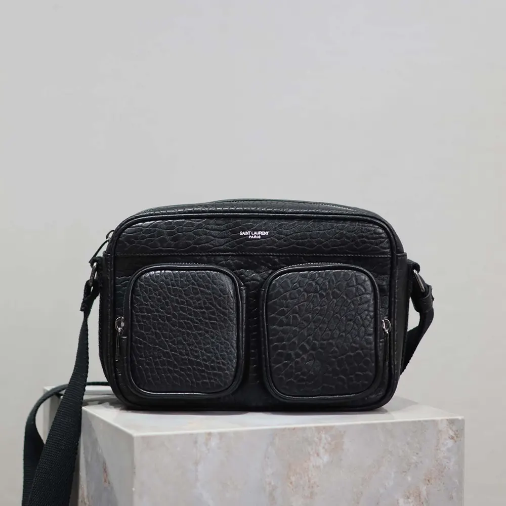 Close-up of silver YSL logo on black grained leather camera bag