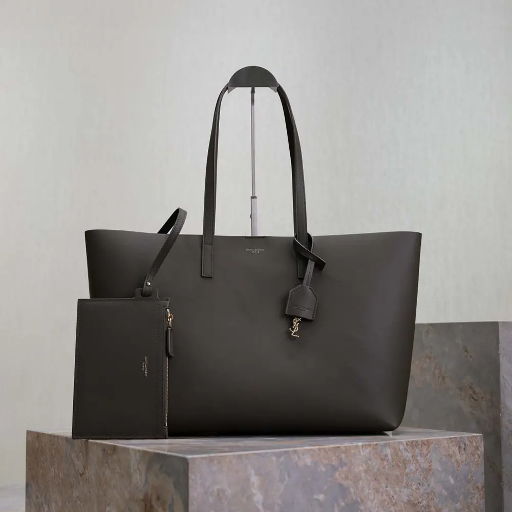 Close-up on gold-tone YSL logo hardware on gray leather bag