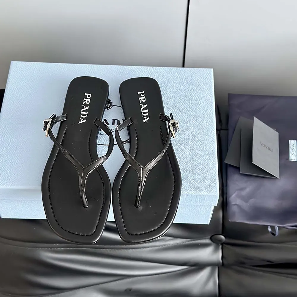 Close-up of black leather thong strap and Prada logo detail sandal