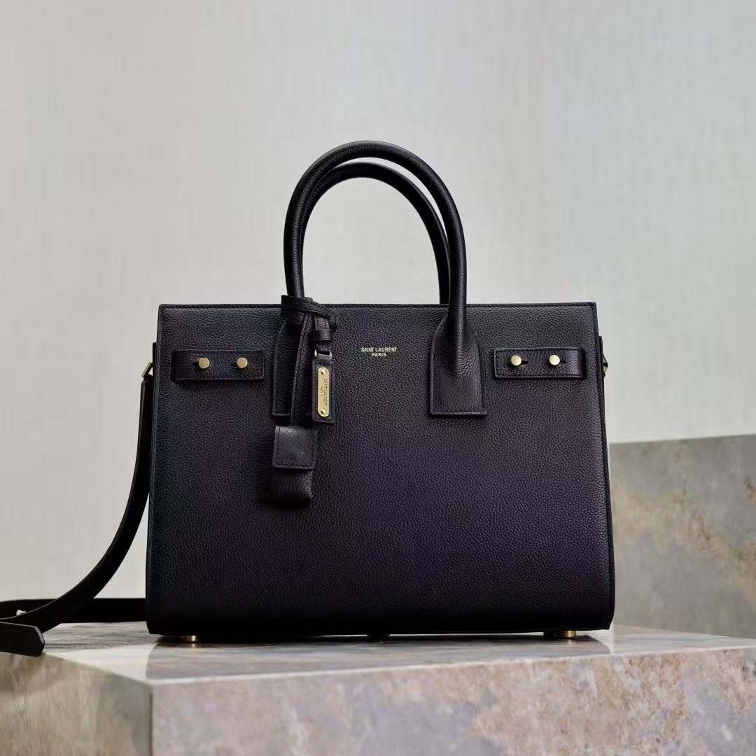 Close-up of gold YSL hardware on black grained leather bag