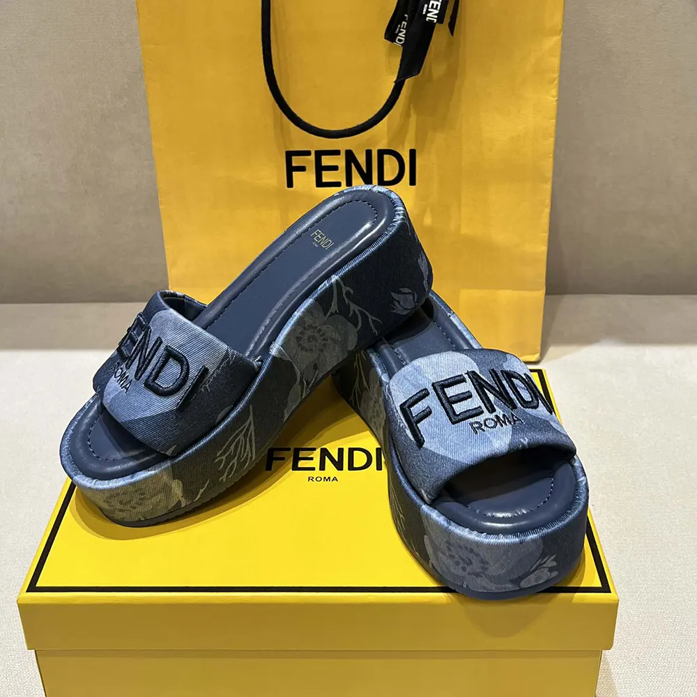 Close-up of gold-tone Fendi logo hardware on blue denim slides