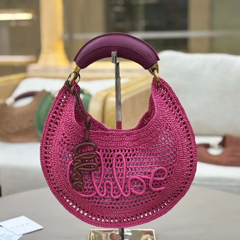 Side angle of Chloe Women Summer Banana Hobo Bag In Raffia-Rose hanging on shoulder