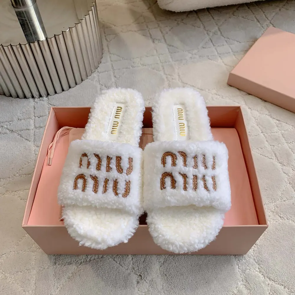 Close-up on embossed leather logo detail of Miu Miu shearling slides