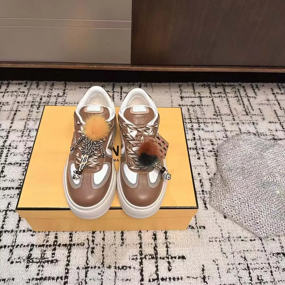 Close-up on the signature charm detail of Fendi brown leather sneakers
