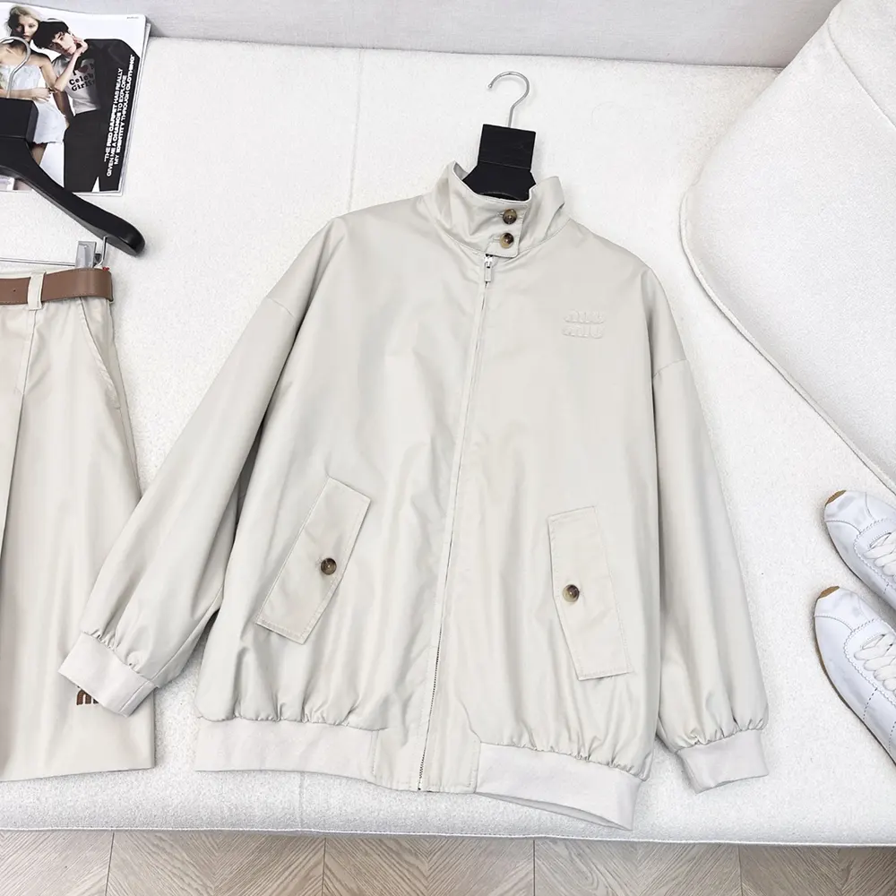 Close-up of zipper and Miu Miu embossed hardware on beige blouson jacket