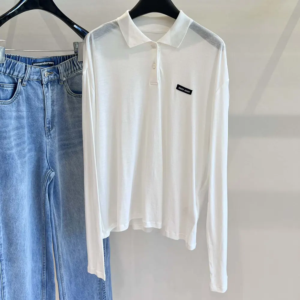 Close-up of Miu Miu logo buttons on white ribbed jersey polo