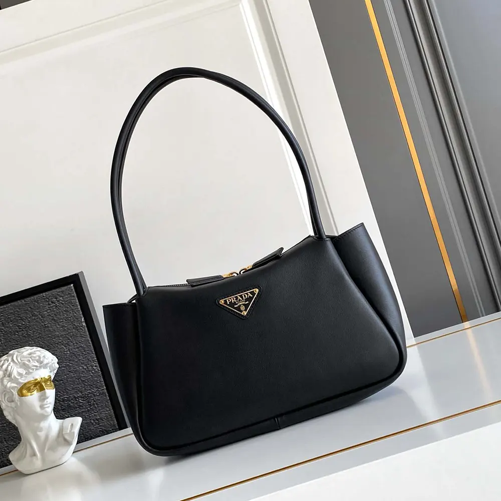 Close-up of gold Prada logo on black leather shoulder bag