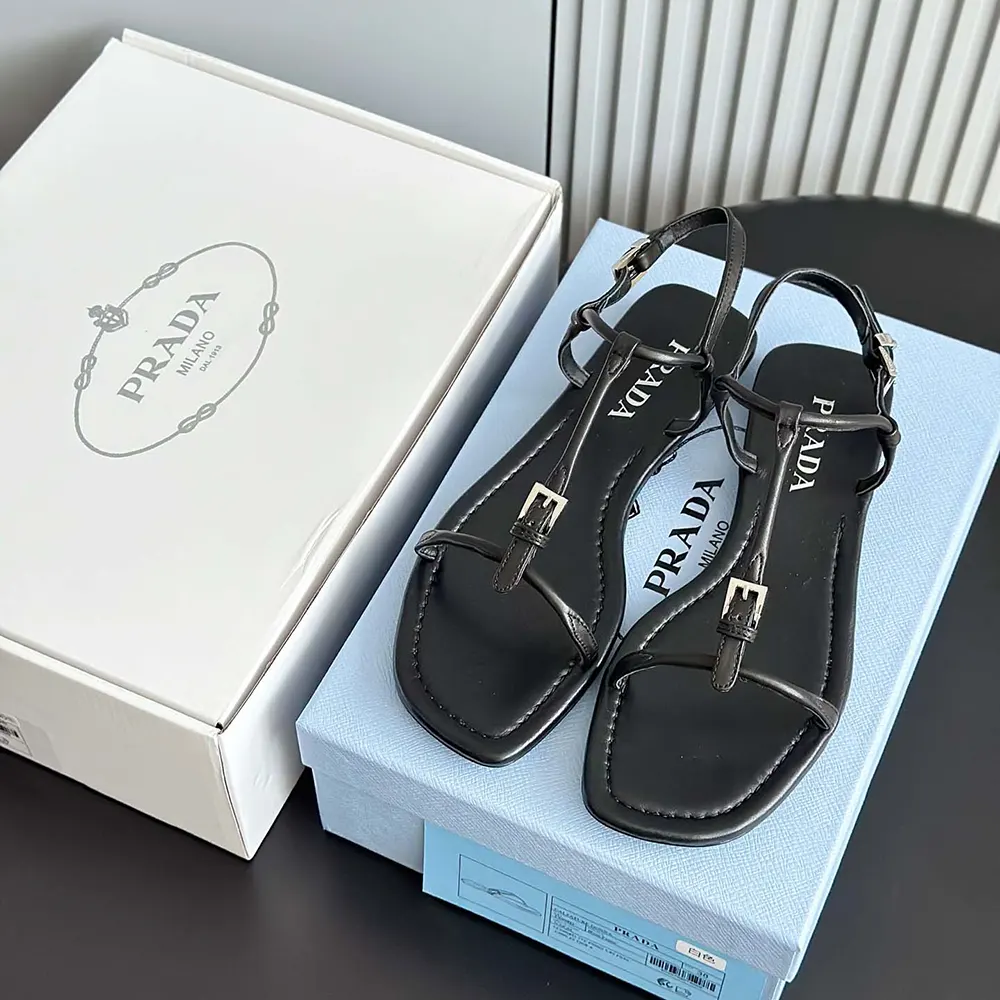 Close-up of black leather and Prada embossed detail on sandals