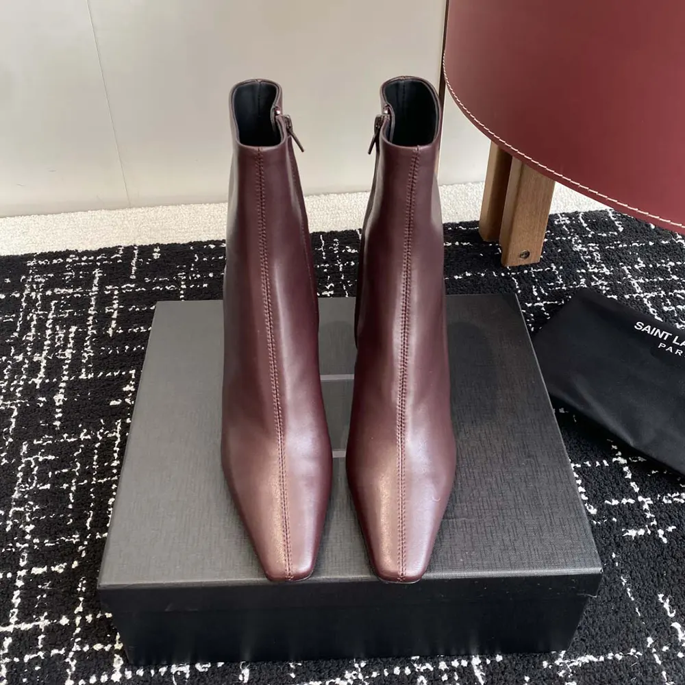 Close-up on gold YSL monogram heel of Jill booties in maroon leather