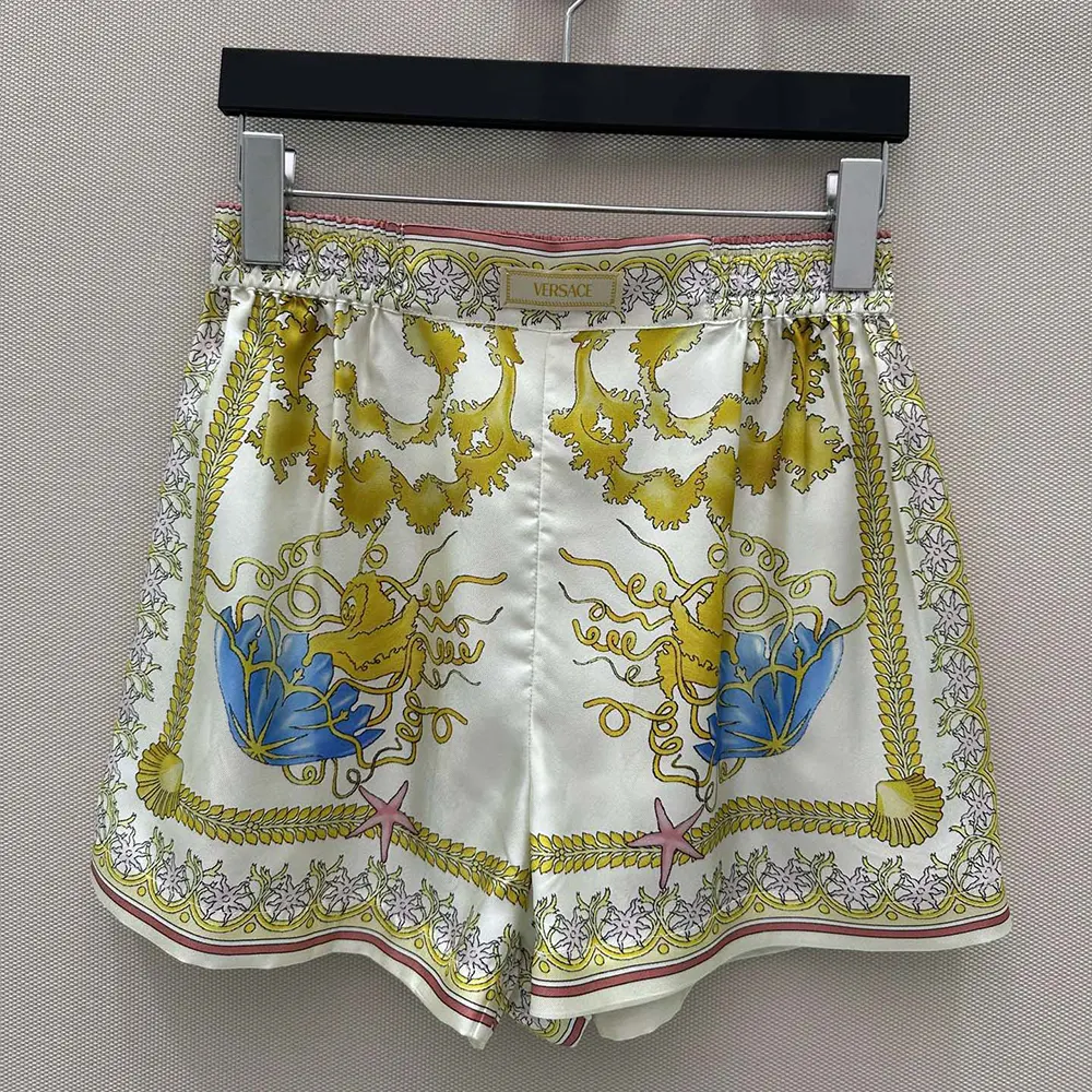 Close-up of golden Barocco print on Versace silk shorts