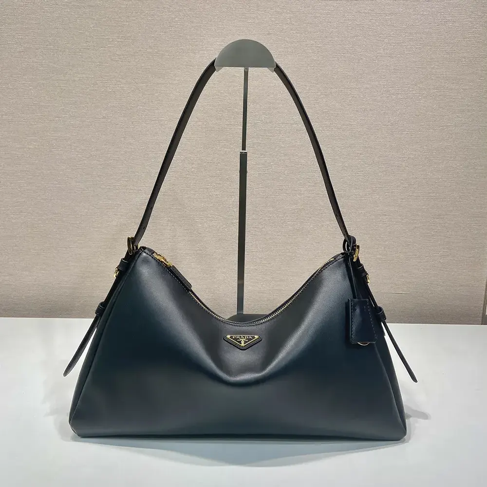 Close-up detail of silver Prada logo plaque on Aimée shoulder bag