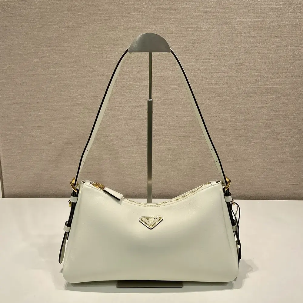 Close-up of gold-tone Prada logo on white leather shoulder bag