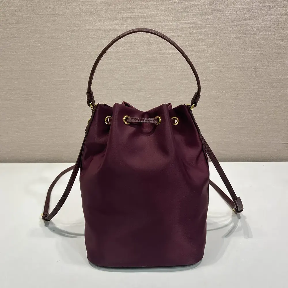 Side angle highlighting maroon color and strap of Prada Women Duet Re-Nylon Bucket Bag-Maroon