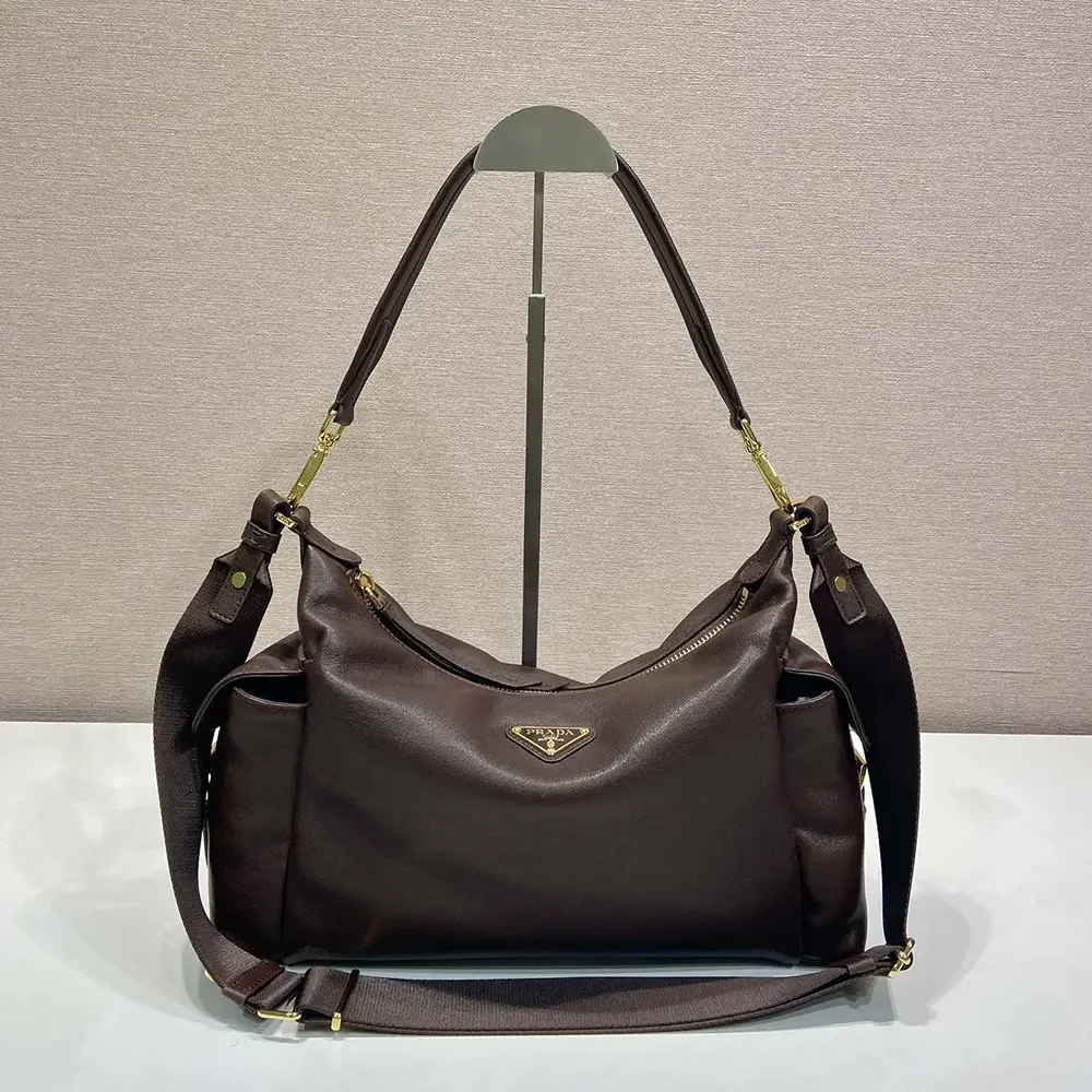 Close-up of antique gold Prada logo hardware on dark brown leather bag