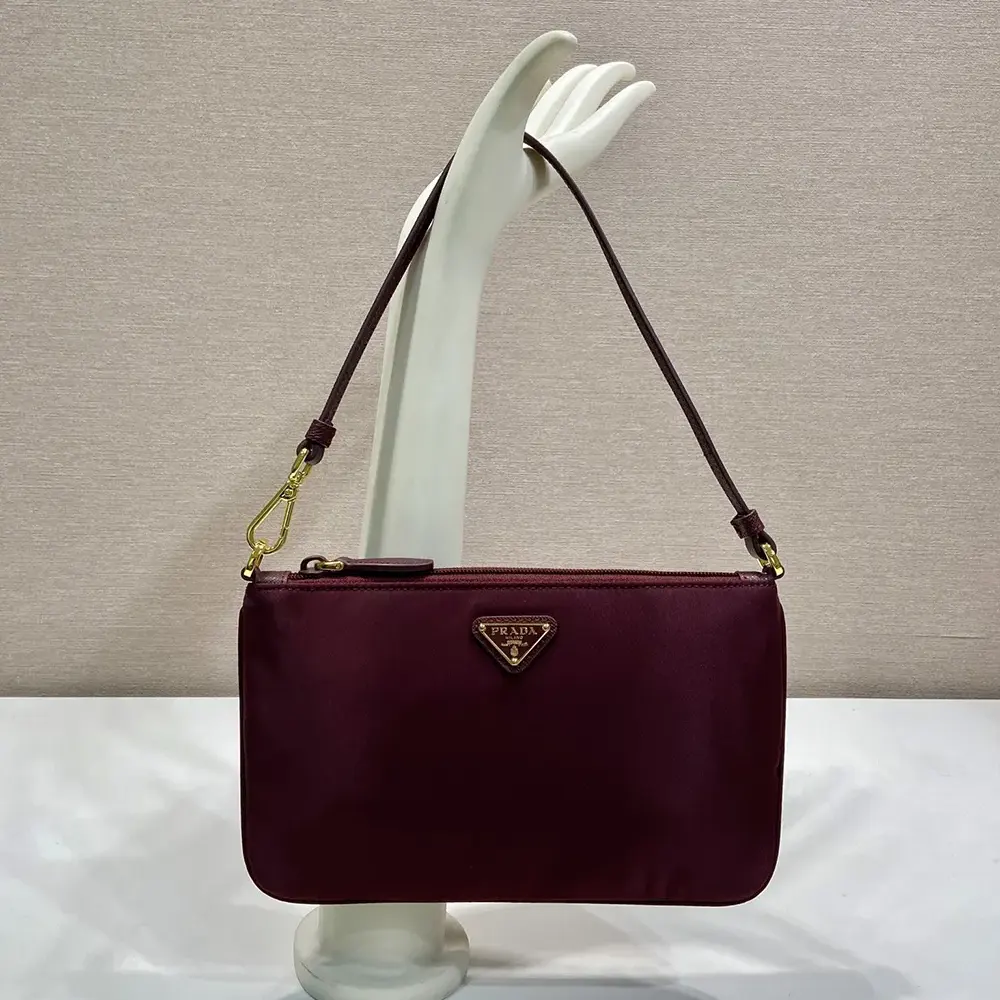 Close-up of enameled metal triangular Prada logo detail on pouch