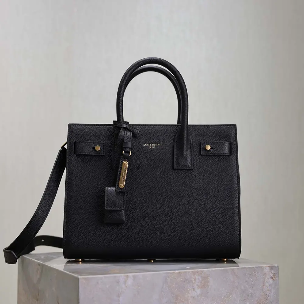 Close-up of gold-tone YSL logo on Baby Sac De Jour black leather