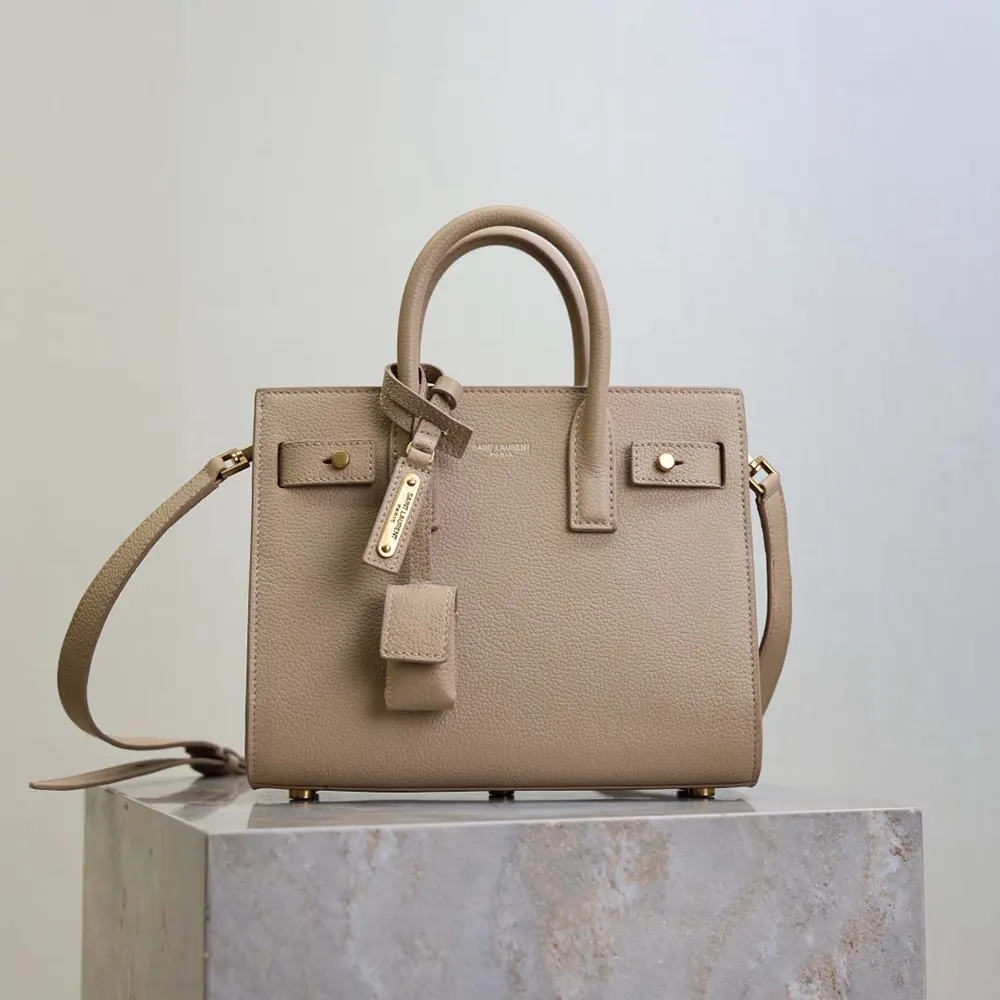 Close-up on gold YSL logo hardware on beige Nano Sac De Jour bag
