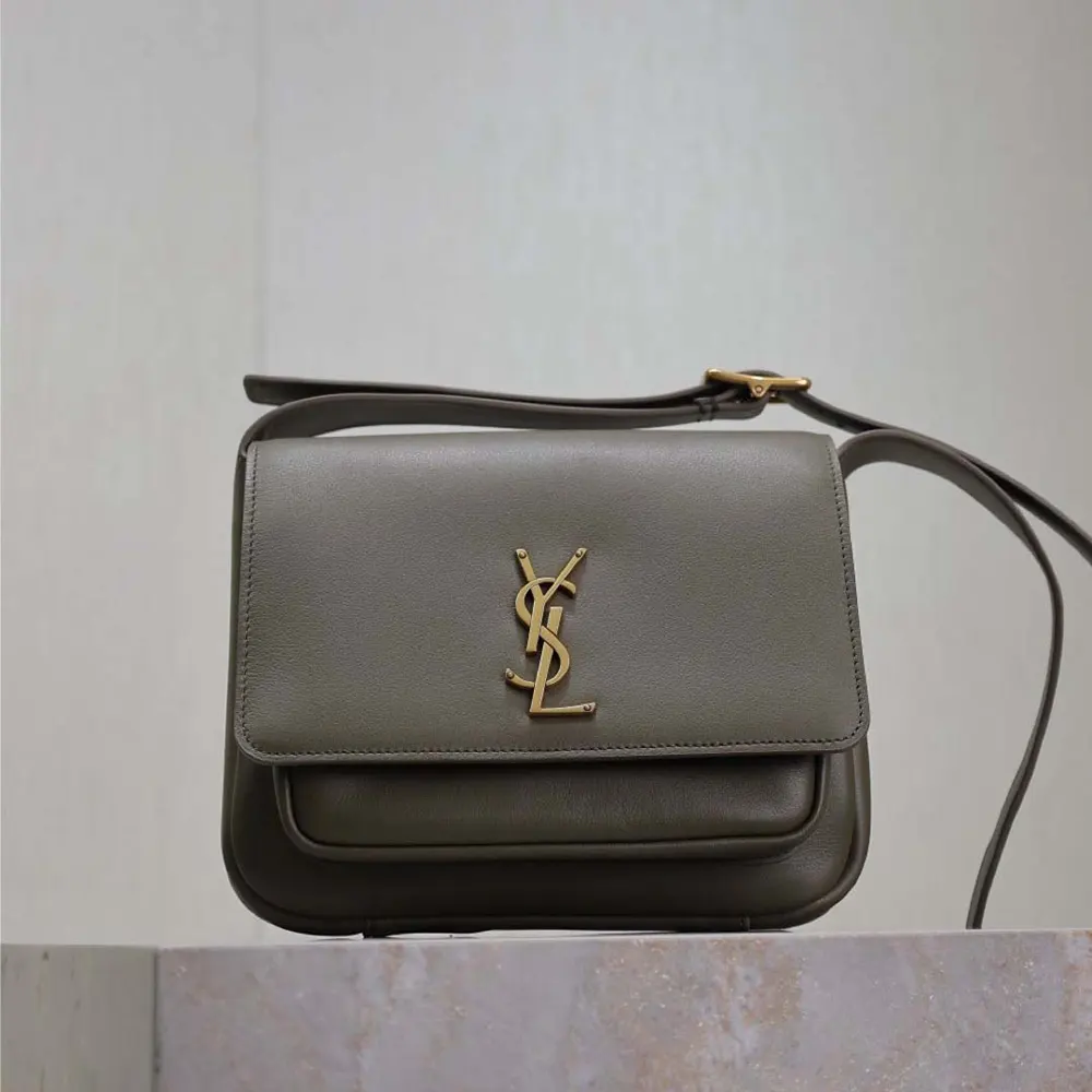 Close-up of gold YSL logo hardware on dark green Niki satchel