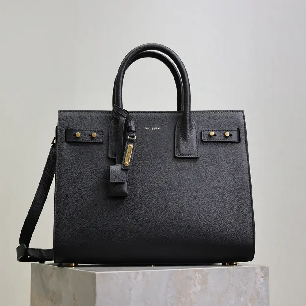 Close-up of gold-tone YSL hardware on black leather bag