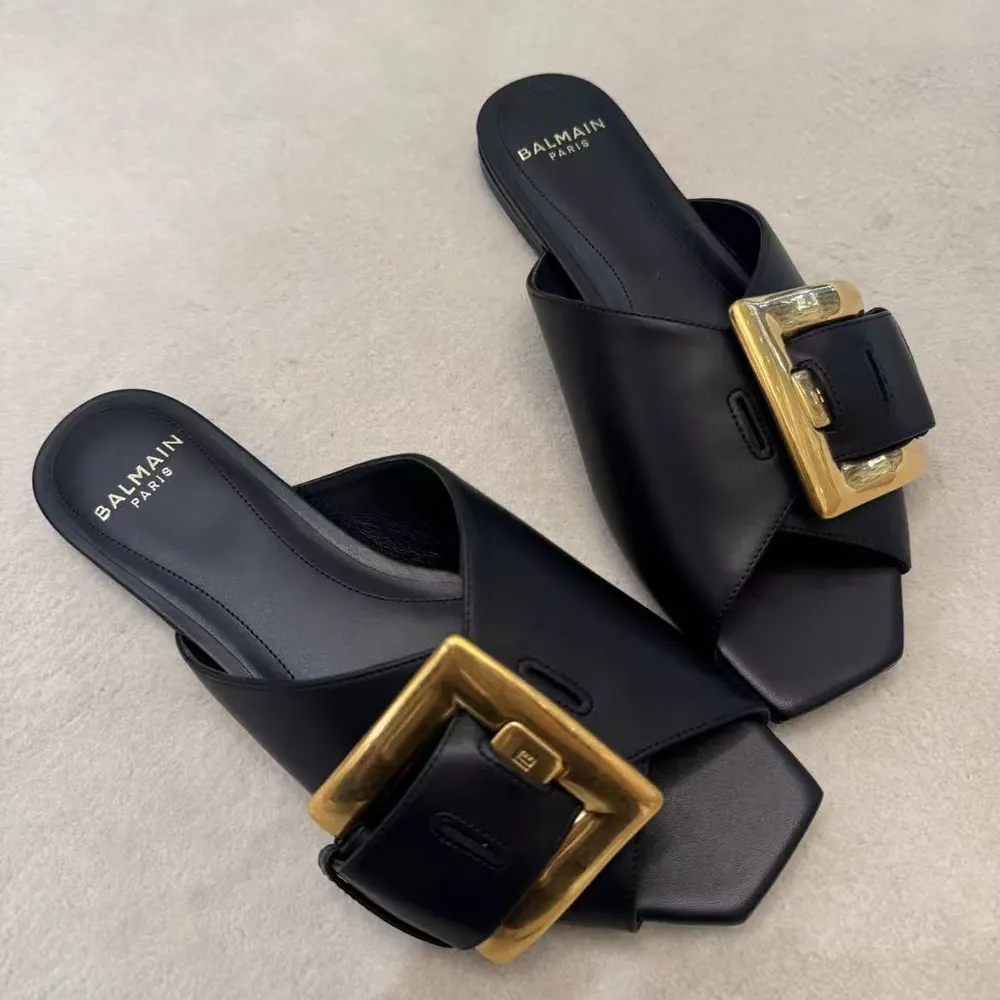 Close-up of Balmain embossed hardware on black leather sandal