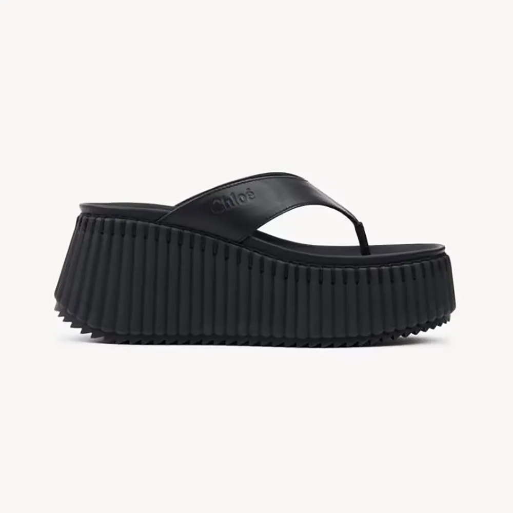Side profile of Chloe Women Nama Wedge Slide-Black showing leather curve