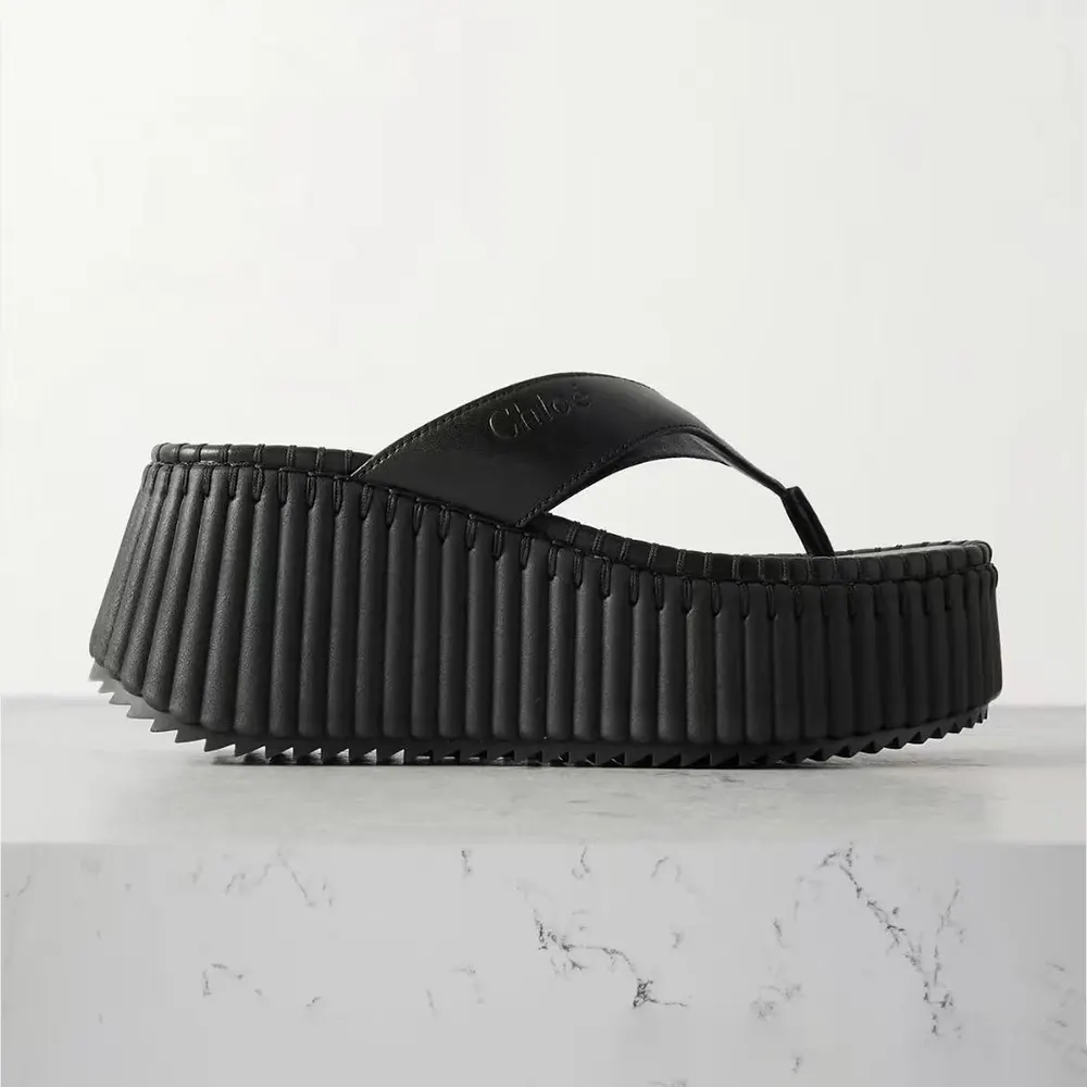 Close-up of black leather and gold logo on Chloe Women Nama Wedge Slide-Black