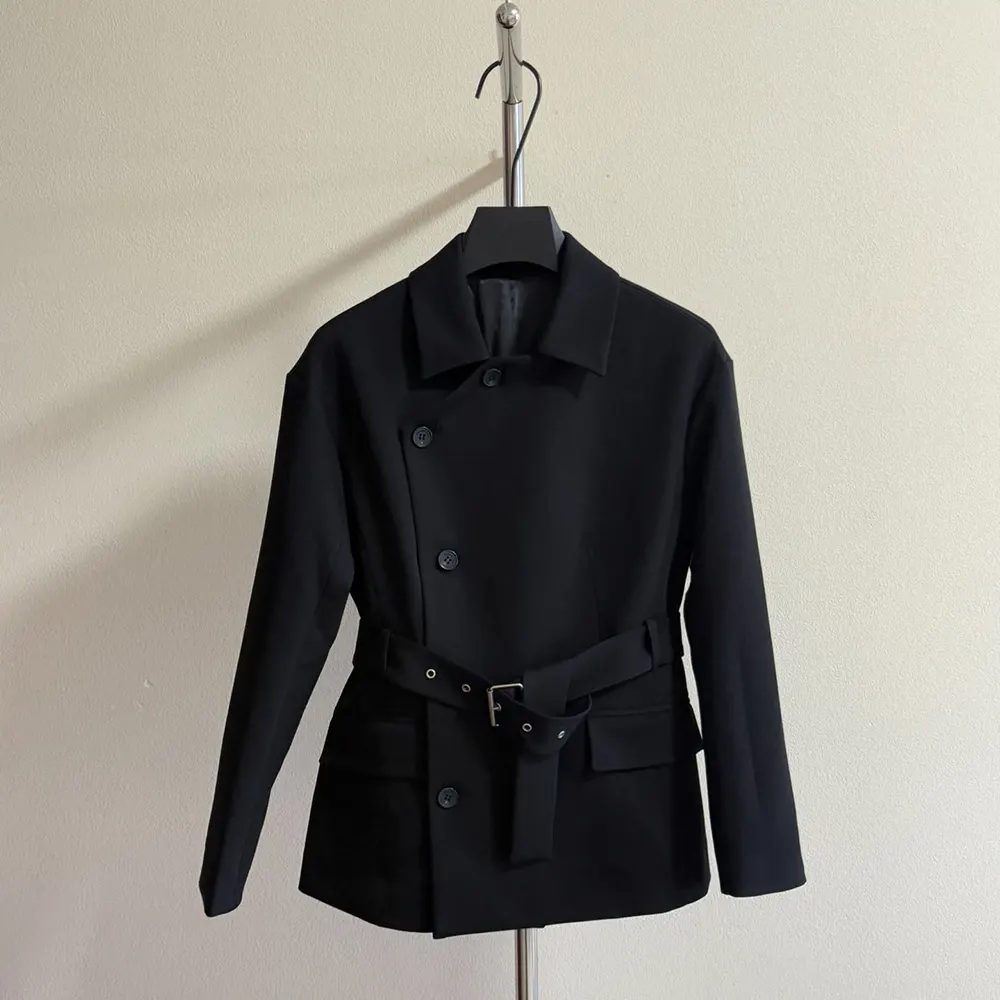 Close-up detail of Dior buttons on black belted jacket