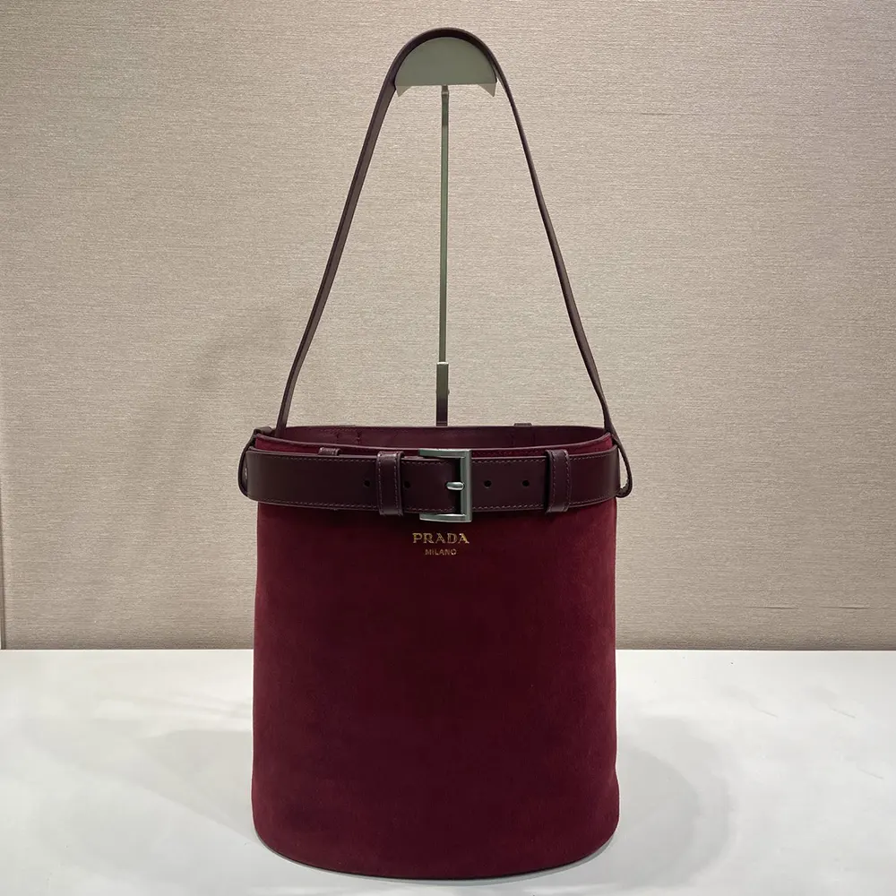 Side angle showing gold-tone hardware on Prada Women Buckle Belted Suede Bucket Bag-Burgundy