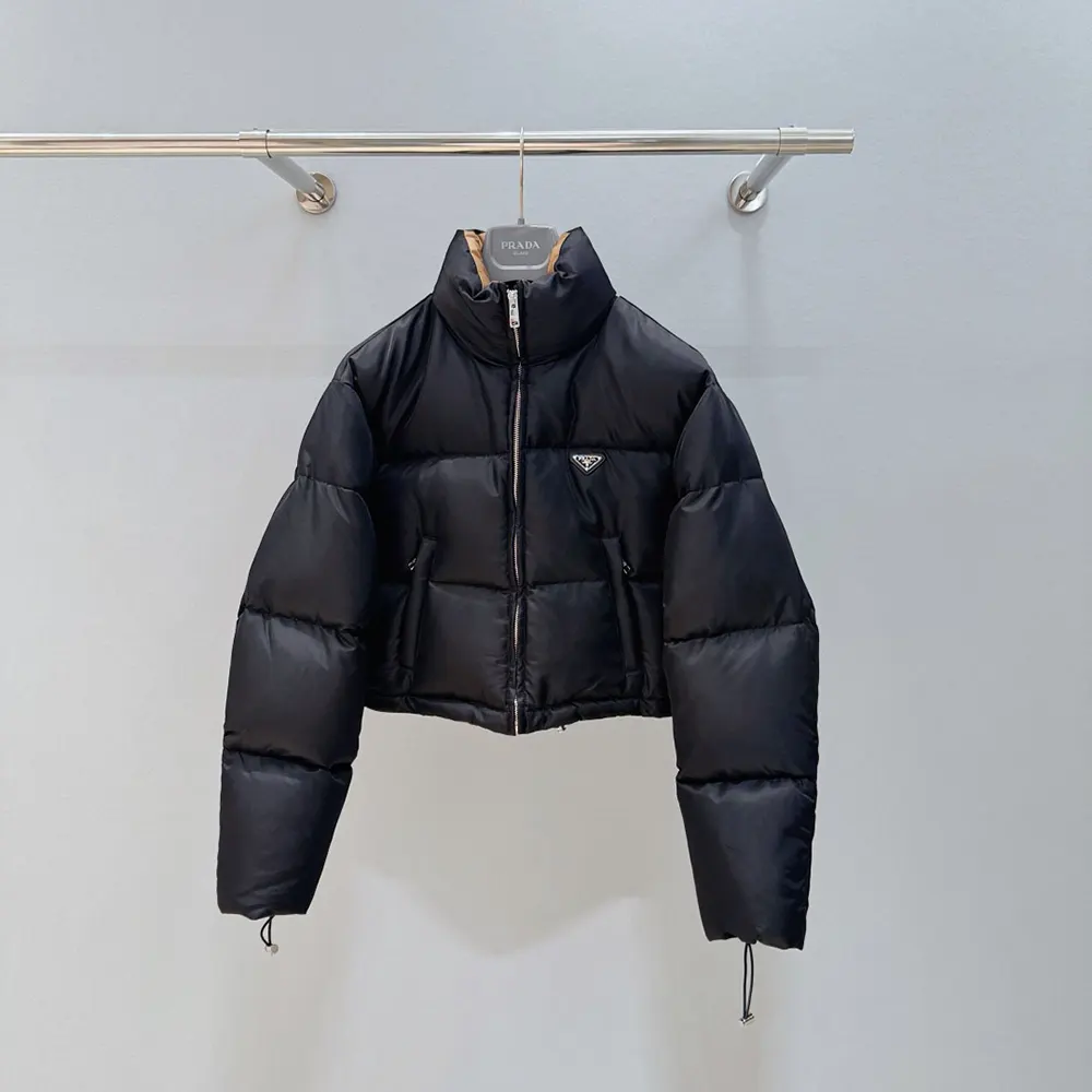 Close-up of signature Prada triangular logo on black cropped down jacket