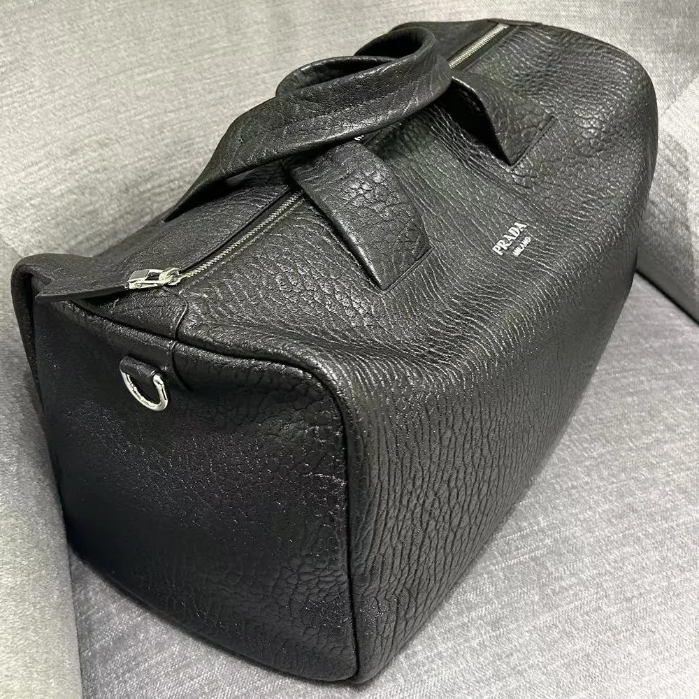 Close-up on silver Prada logo hardware on black nappa leather duffle bag