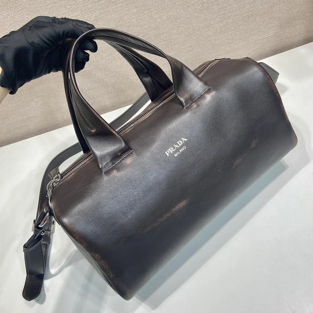 Side angle showing silhouette and adjustable strap of Prada dark brown duffle