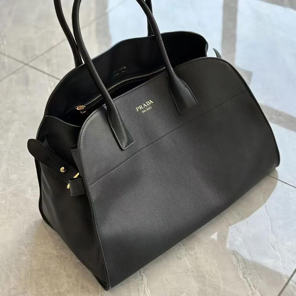 Close-up of silver-tone Prada logo hardware on black leather tote