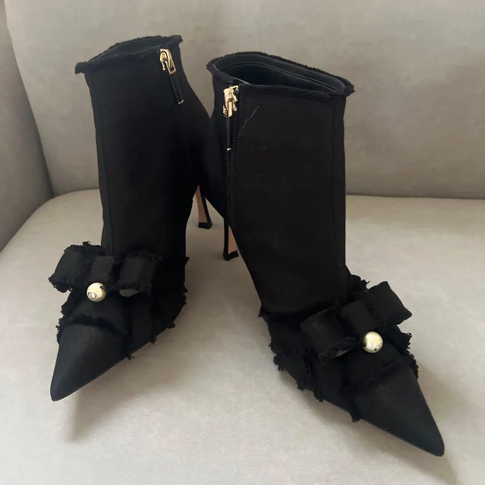 Close-up detail of fringed grosgrain and Dior logo on black ankle boots
