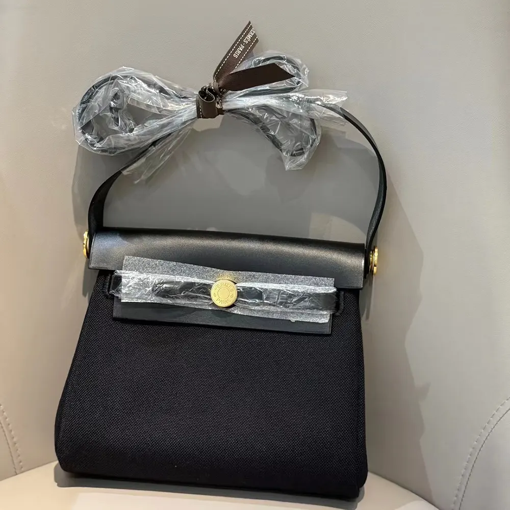 Side angle of Hermes Women Herbag Zip 20 Bag-Black/Gold highlighting leather texture