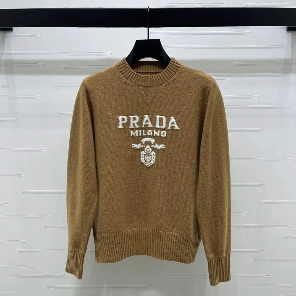 Close-up of embroidered Prada logo on camel brown crew-neck sweater