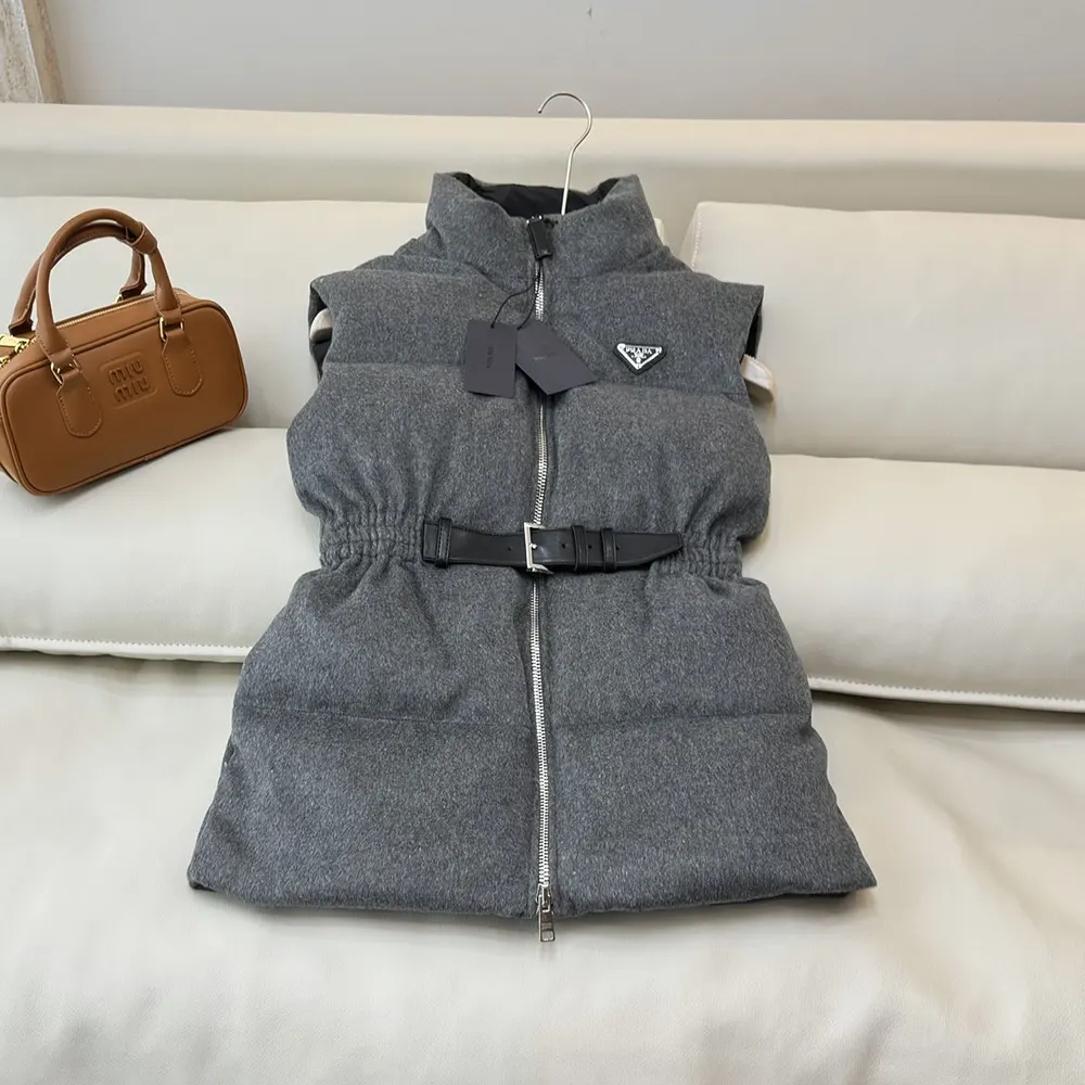 Close-up on silver Prada logo hardware on grey down vest
