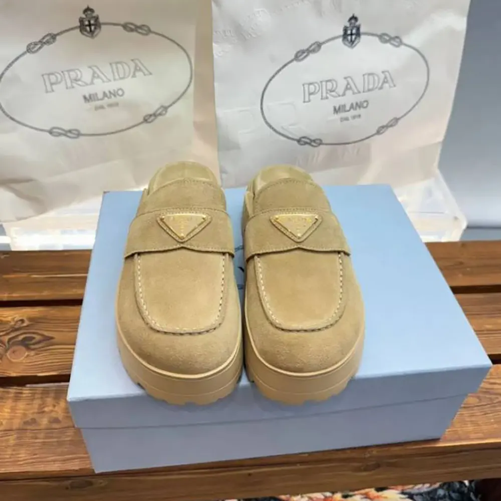 Close-up of enameled metal triangle logo on Prada flatform mules
