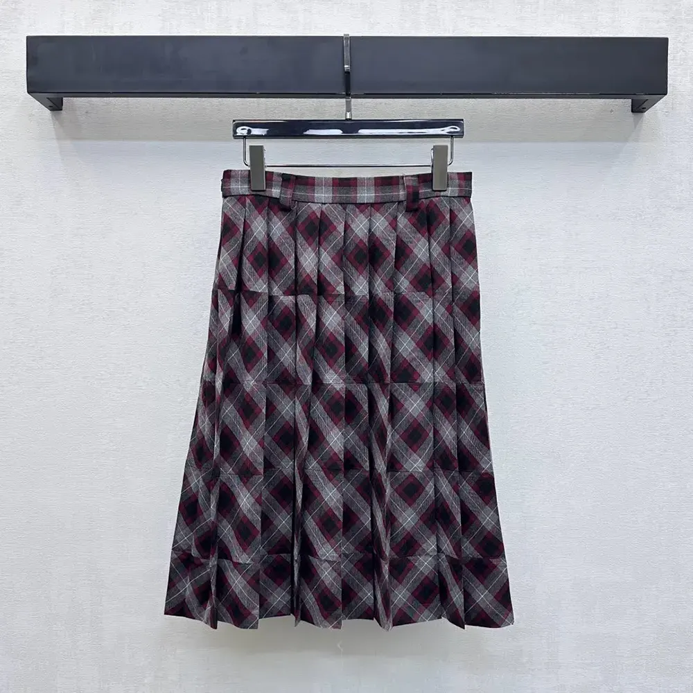 Close-up of tartan patchwork and Prada logo hardware detail on skirt
