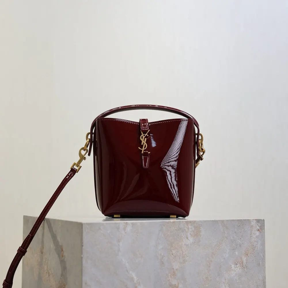 Close-up of gold YSL logo on maroon patent leather mini bag