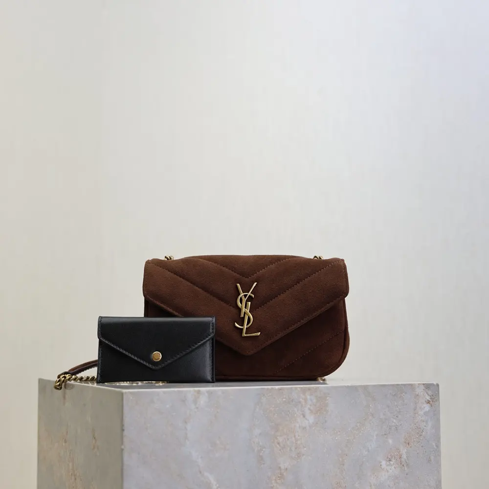 Close-up of gold YSL logo hardware on suede brown bag