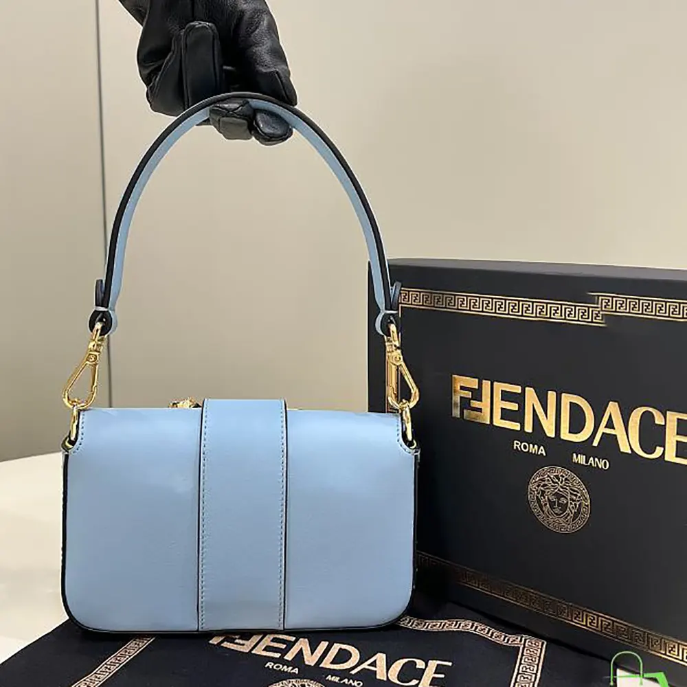 Close-up of gold Fendace brooch hardware on blue leather bag