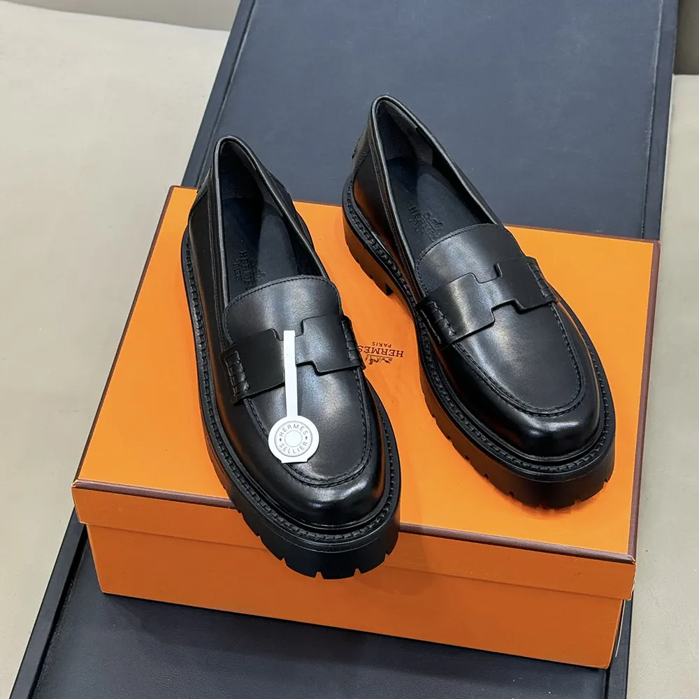 Close-up of black calfskin and Hermes signature hardware detail on loafer