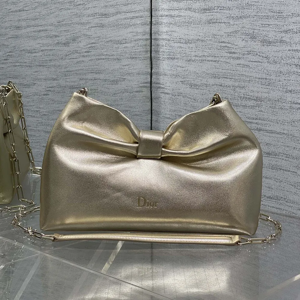 Close-up of signature Dior bow hardware on gold laminated lambskin bag