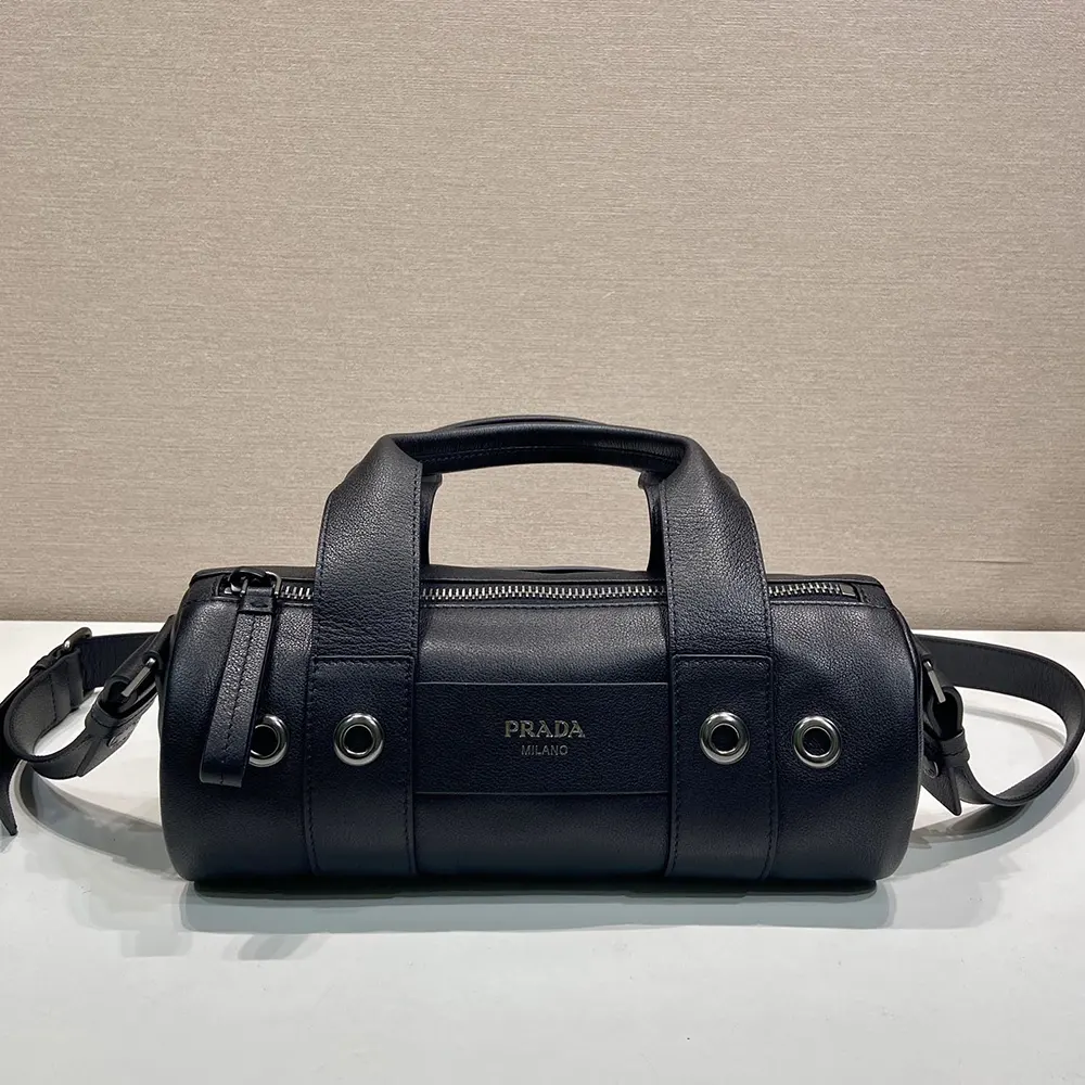 Close-up of Prada logo plaque on black leather top-handle bag