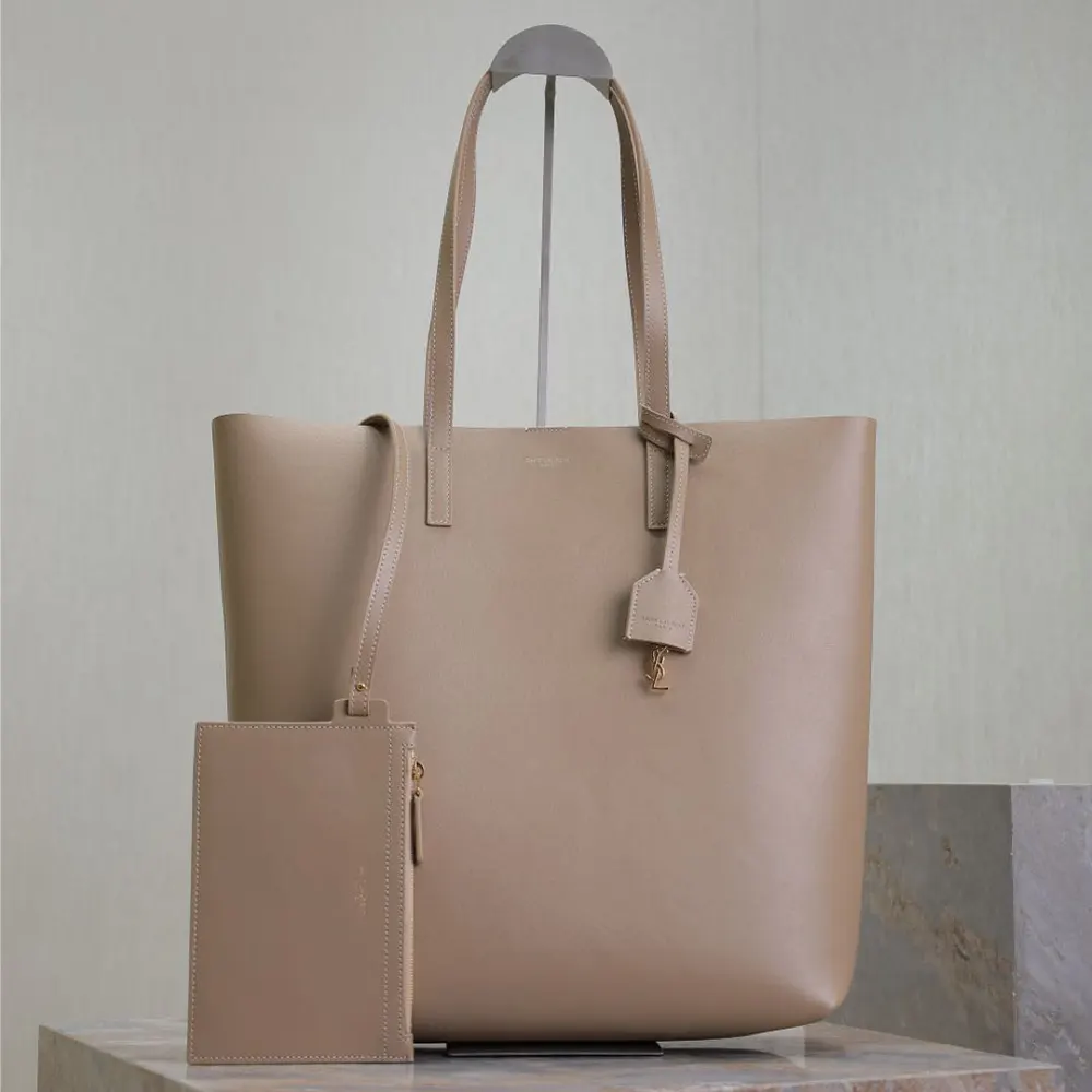 Close-up of gold YSL logo hardware on leather sandy bag